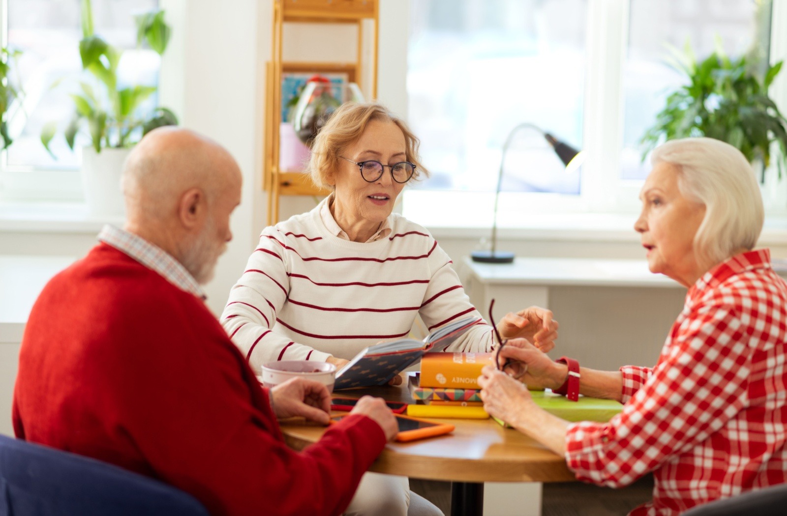 A group of 3 senior friends sit at a table together and have a conversation
