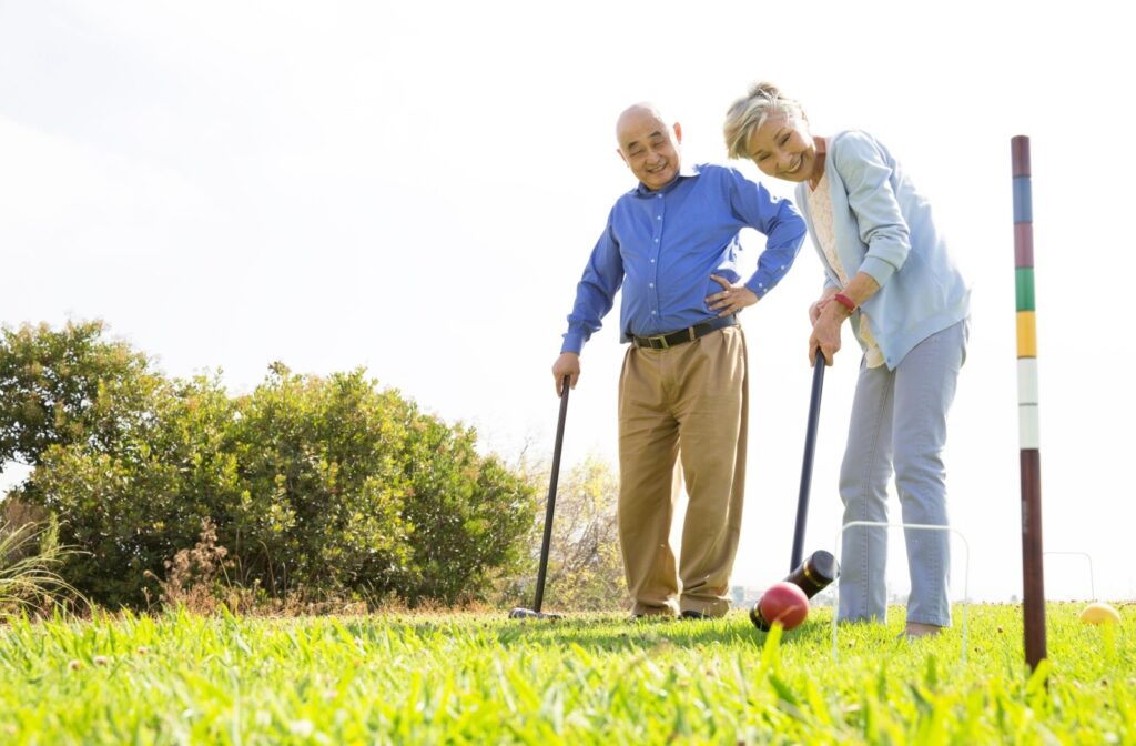 An older couple plays a game of croquet on a bright, sunny spring day