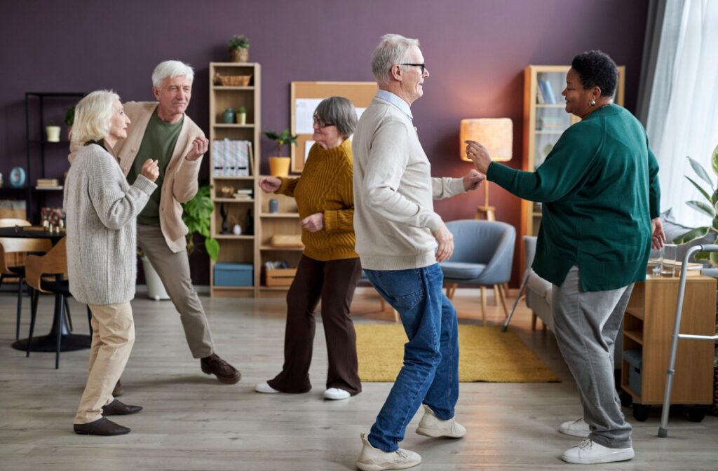 A group of senior living residents dance together during a social exercise class